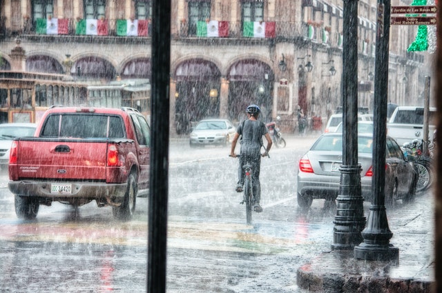 person riding a bike through a city during a heavy rainstorm