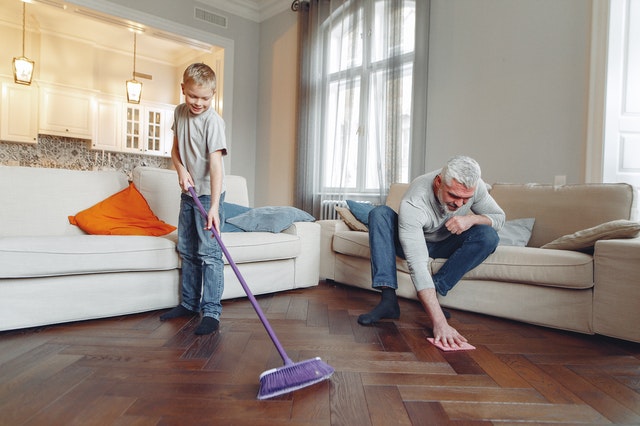 little boy and father cleaning living room floor