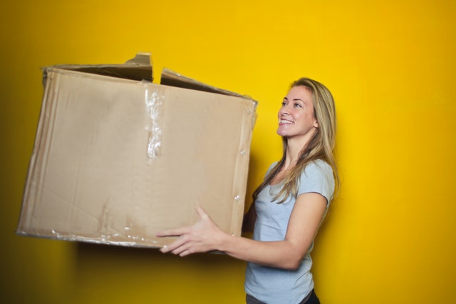woman holding a large brown moving box